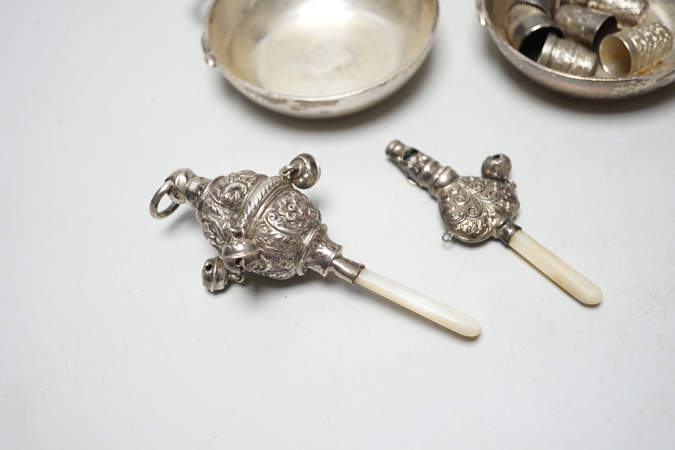 A pair of George V silver taste vin, D & J Welby Ltd, diameter 82mm, a late Victorian mother of pearl handled repousse silver child's rattle, one other larger similar silver rattle and eight thimbles including five silve